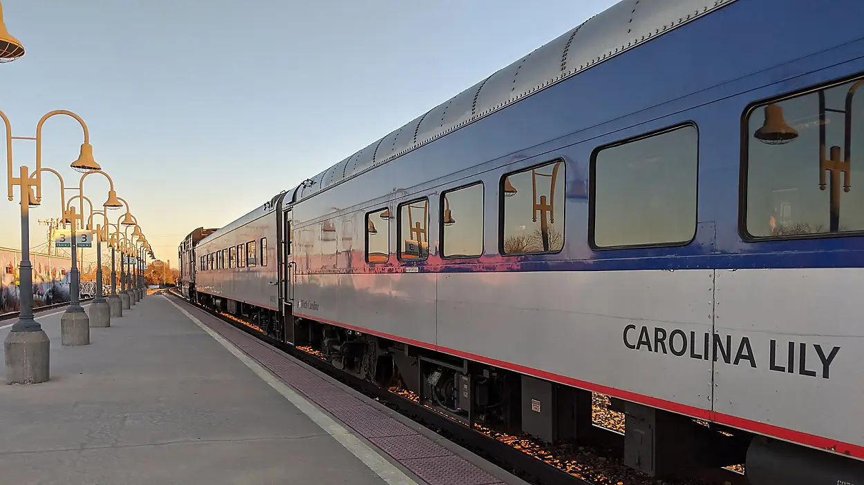 Carolina Lily passenger train parked at a station platform with lamps and clear sky