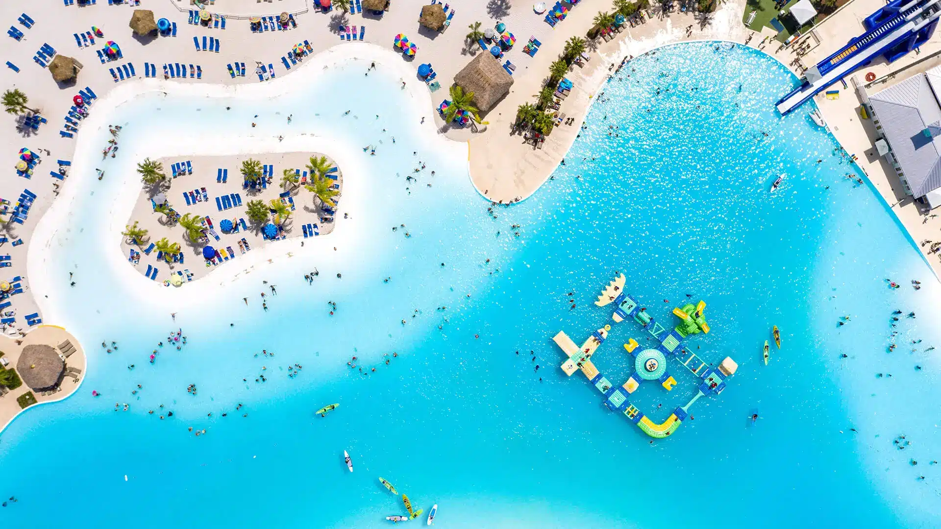 Aerial view of a bright turquoise crystal lagoon concept with sandy beaches, lounge areas, and floating water features, illustrating the planned development in Huntersville