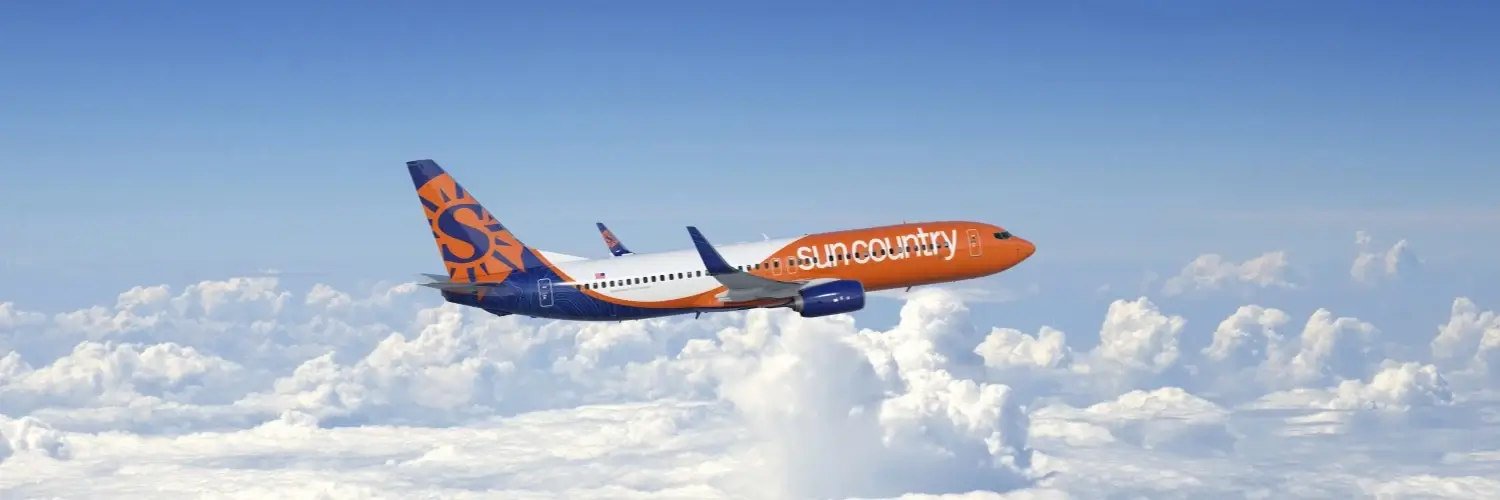 A Sun Country Airlines plane flying above the clouds, highlighting new low-cost direct flight options from Charlotte
