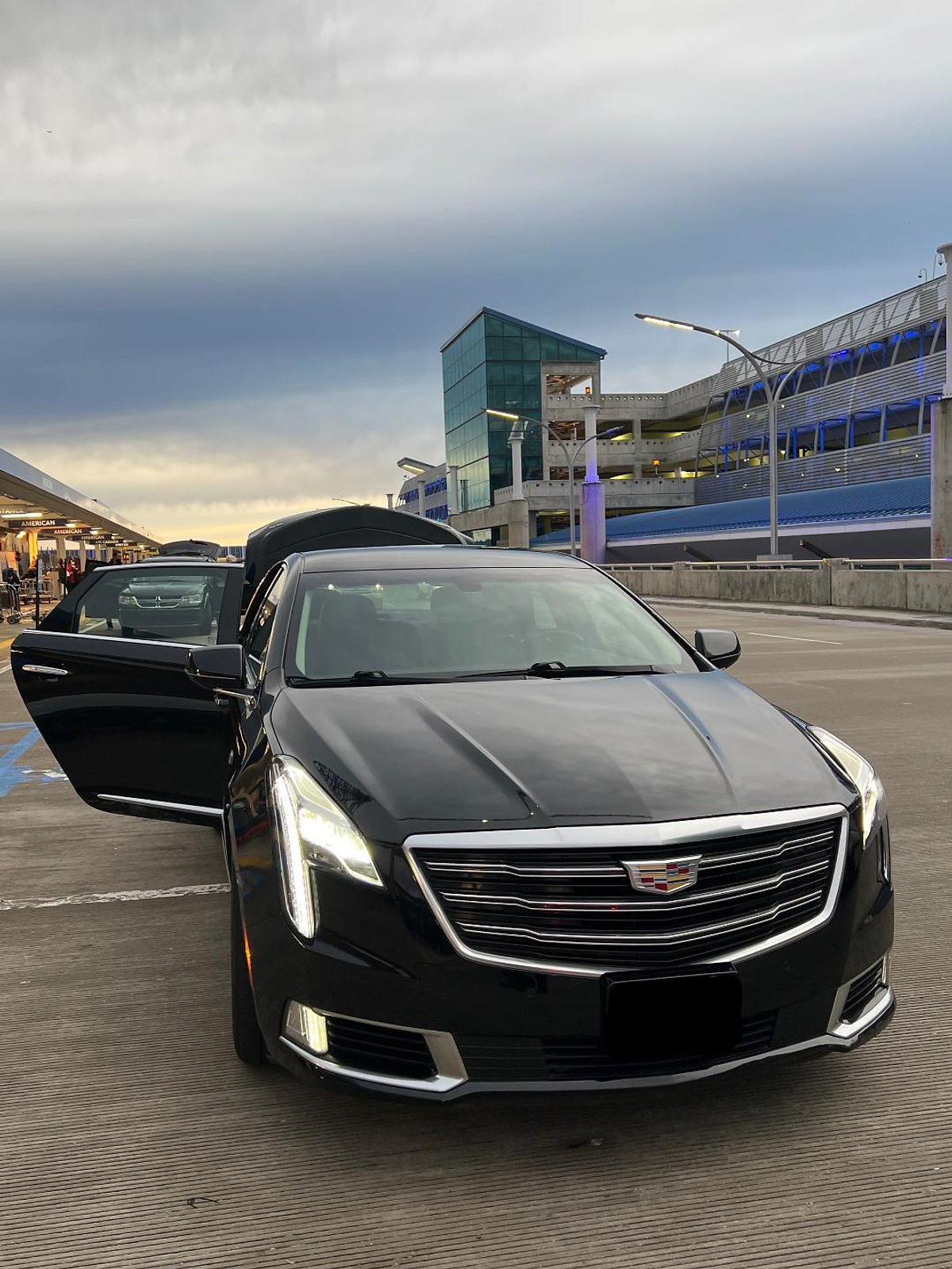 Luxury black sedan airport pickup at Charlotte Douglas International Airport terminal