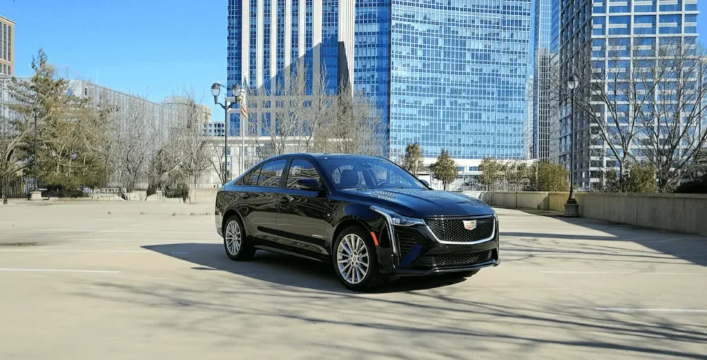 Black executive sedan parked in front of a modern cityscape.