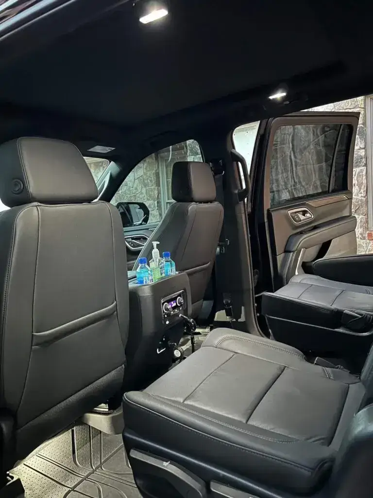 Interior of an executive SUV showing black leather seats and center console with water bottles.