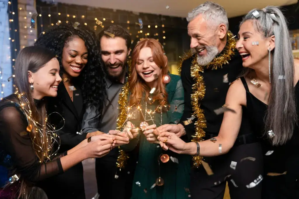 A group of people celebrating indoors with sparklers and confetti.